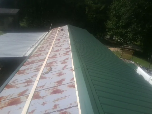 Old rusted panels beside newly installed green metal roofing — Wind Damage Roof Repair by Roofing Brothers in Glenolden