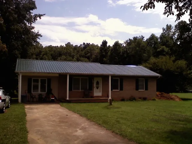 Dark green metal roof on a brick ranch with a covered porch in Glenolden