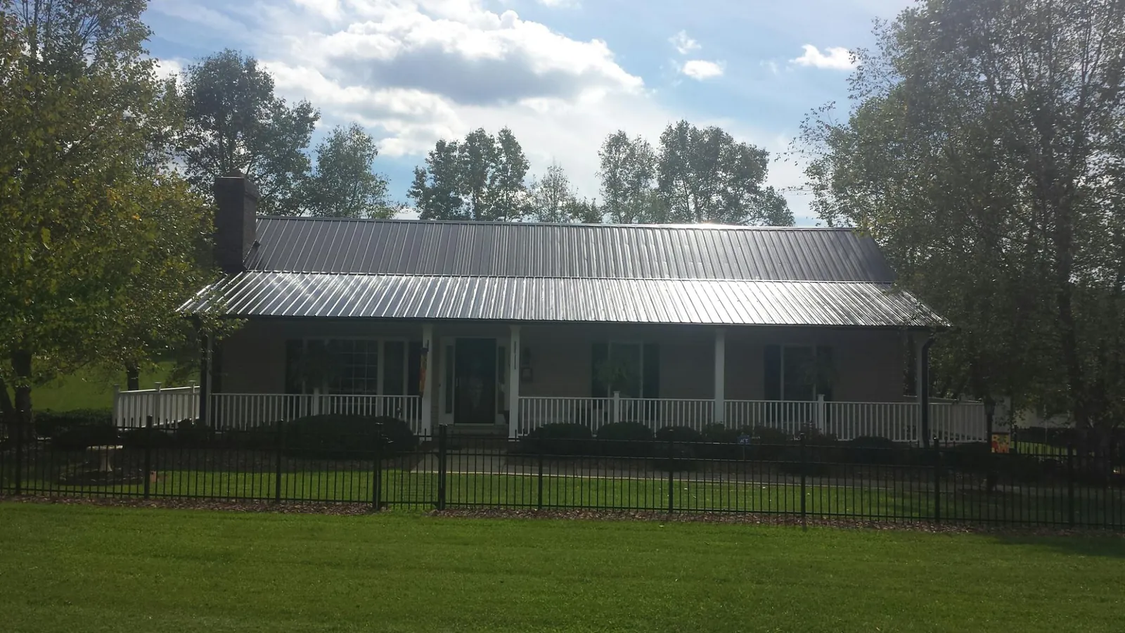 Gray metal roof on a brick ranch with a full width front porch — Gutter Guard Installation work by our crew in Glenolden