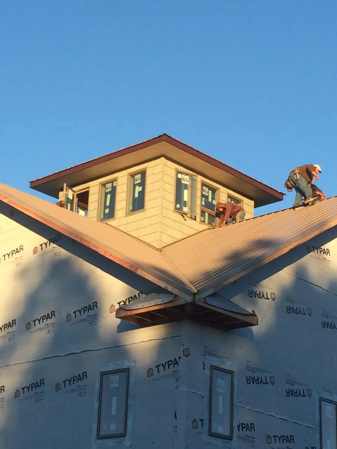 Roofers working around a rooftop cupola on a new metal roof at sunset — Roof Waterproofing in Glenolden by Roofing Brothers